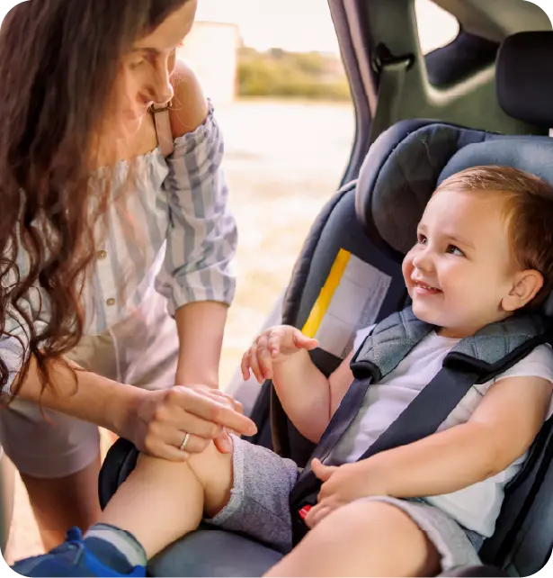 Niña sentada en una silla infantil dentro de un coche.