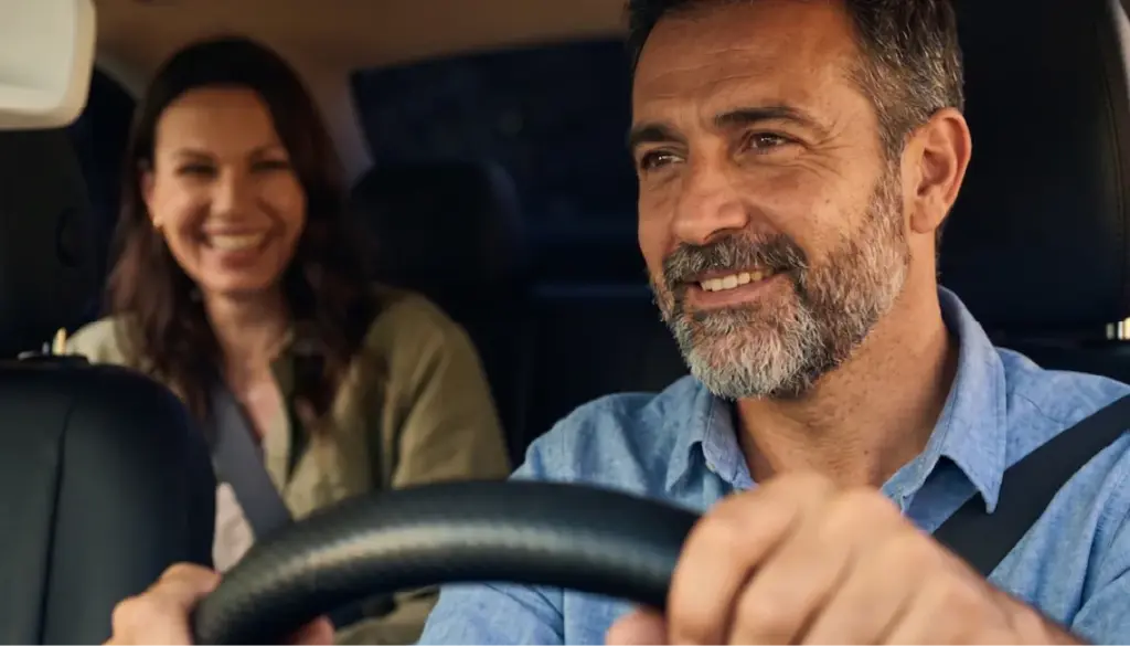 Conductor al volante con una pasajera en el asiento trasero.