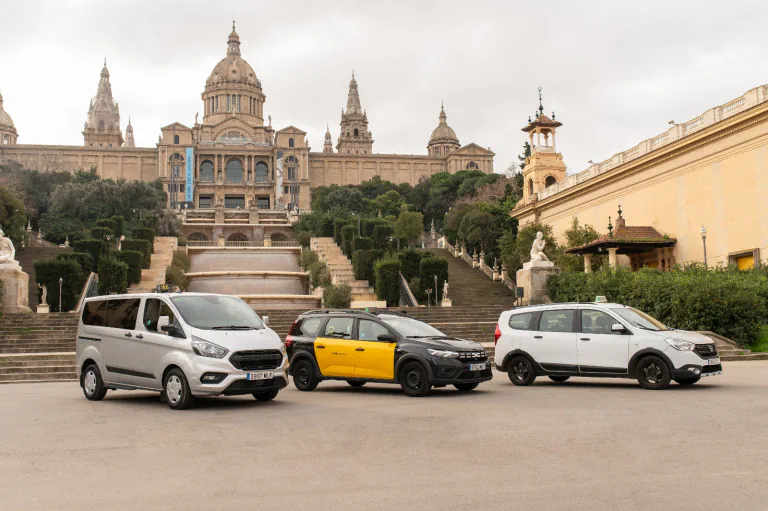 Tres taxis de distintos tamaños estacionados frente al Palau Nacional de Montjuïc.